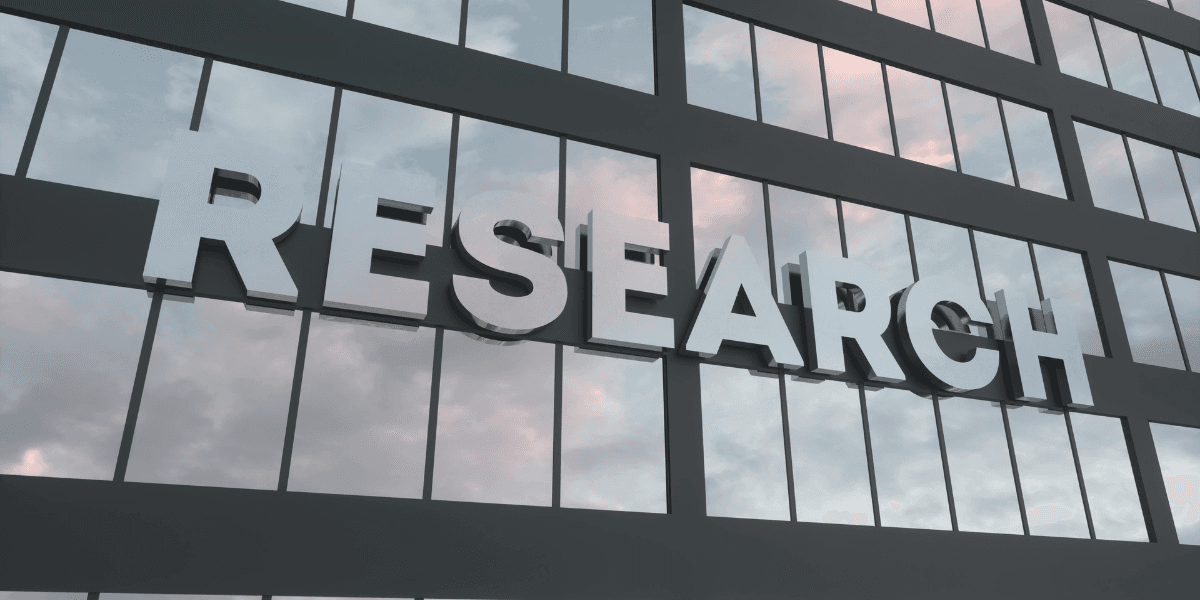 Building facade with large reflective letters spelling "RESEARCH" against a cloudy sky.
