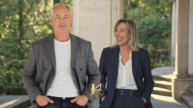 A professional man and woman smiling while walking outdoors, dressed in business attire.