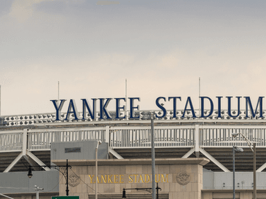 Yankee Stadium exterior with stadium signage above the entrance under an overcast sky.