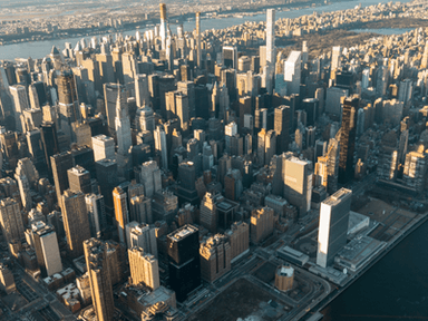Aerial view of a dense New York City skyline with skyscrapers and river.