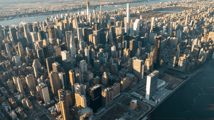 Aerial view of a dense New York City skyline with skyscrapers and river.