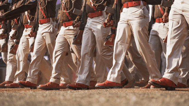 Soldiers in uniform marching in formation, showcasing polished boots and rifles.