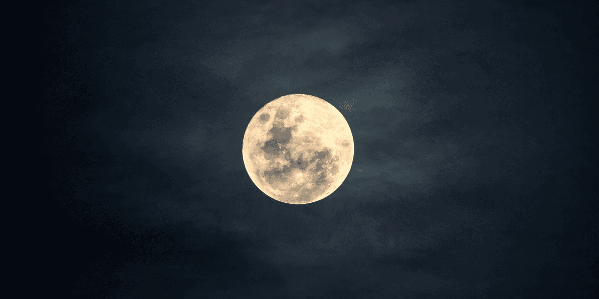 Full moon against a dark sky with subtle cloud textures surrounding it