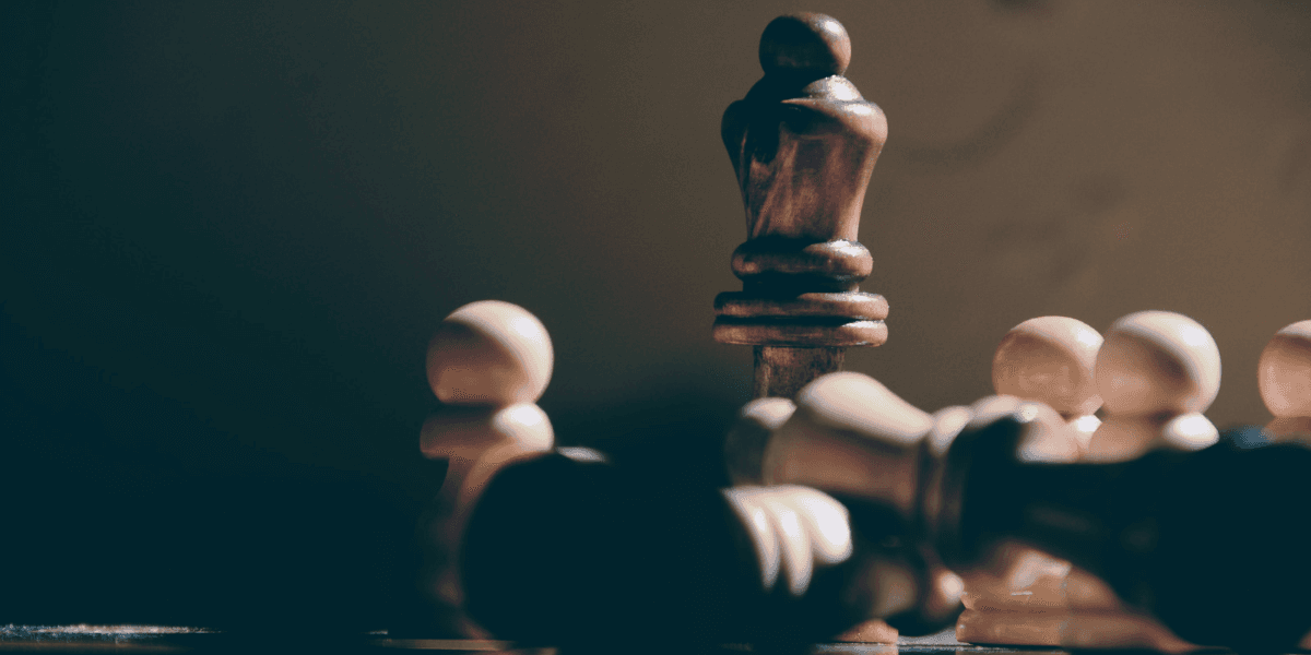 A close-up of a wooden chessboard with a king and fallen pieces