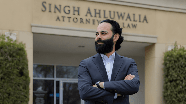 Deepak Ahluwalia, attorney at Singh Ahluwalia Law, confidently stands in front of the firm's office, showcasing professionalism and dedication.