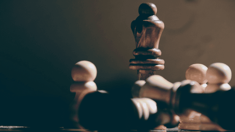 A close-up of a wooden chessboard with a king and fallen pieces