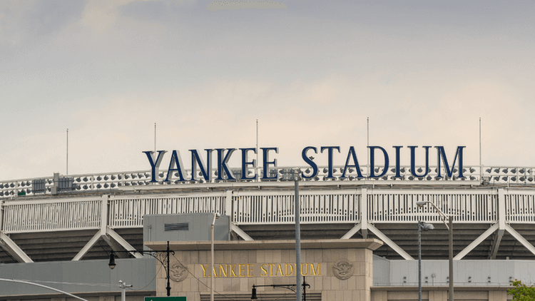 Yankee Stadium exterior with stadium signage above the entrance under an overcast sky.
